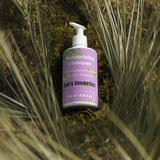Purple shampoo bottle labeled 'Kids' Cosmetics' on a natural background with plants.