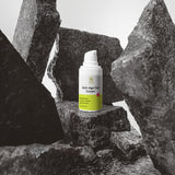 Anti-aging cream bottle on a rocky surface with a gray background